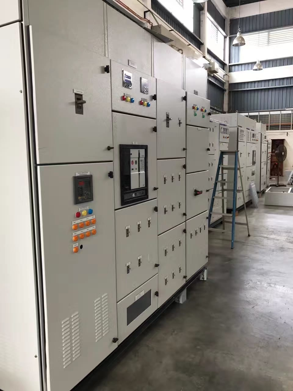 Electrical control panels in a light industrial setting; gray metal cabinets, various gauges, and controls.