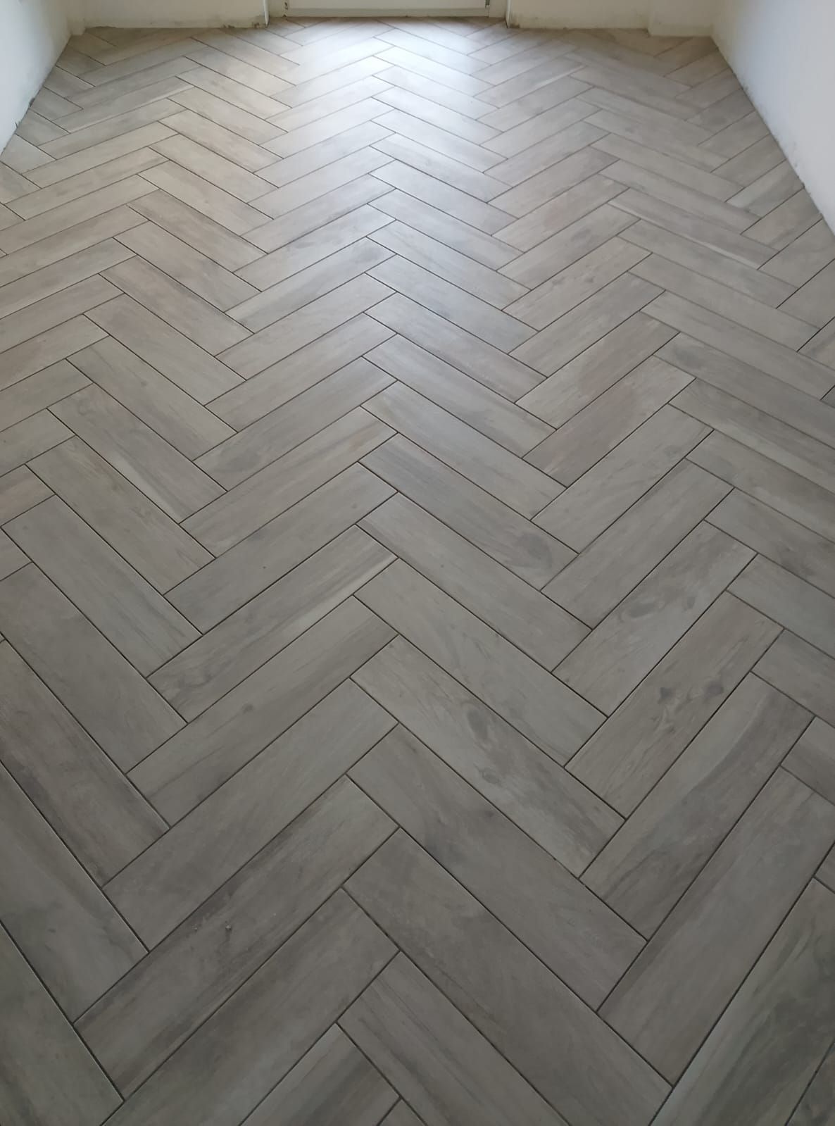 Una stanza con pavimento effetto legno grigio chiaro posato a spina di pesce.
