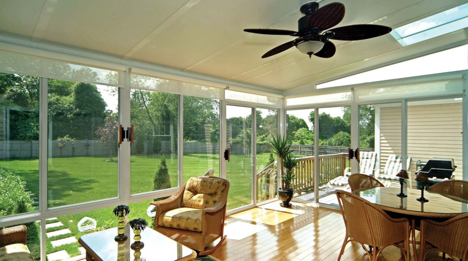 A screened in porch with a ceiling fan and a table and chairs