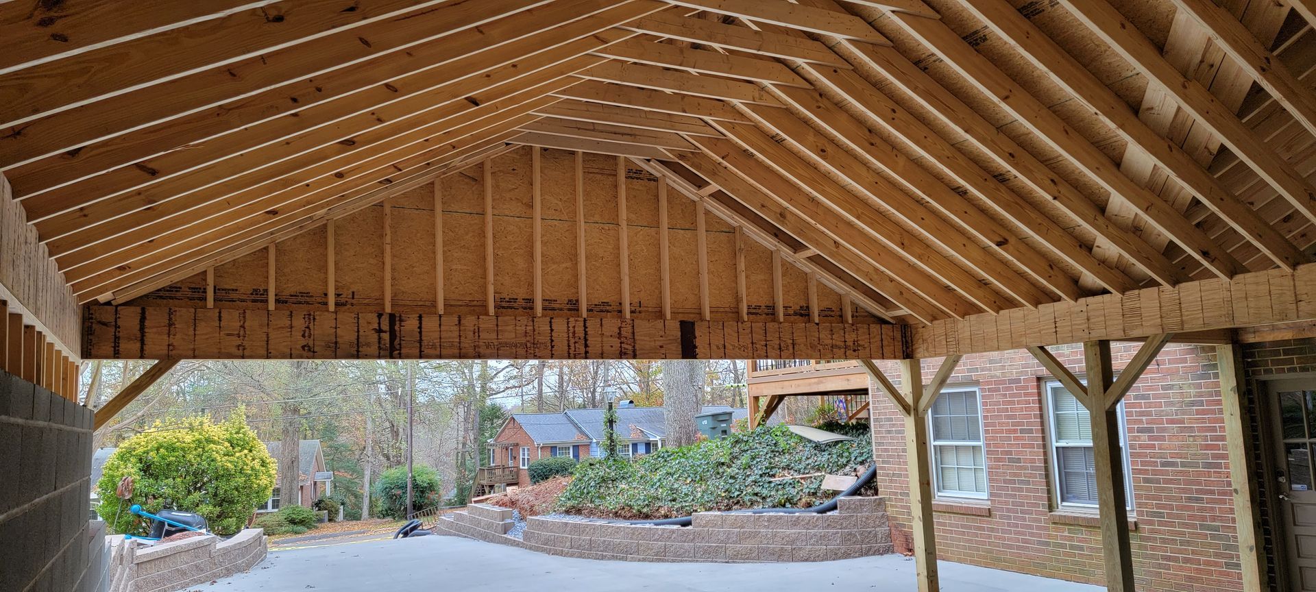 A wooden carport is being built in front of a brick house.