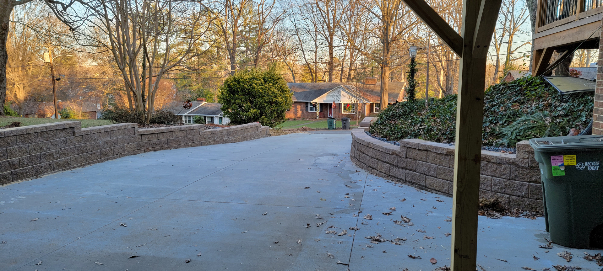 A driveway leading to a house with a trash can in the foreground.