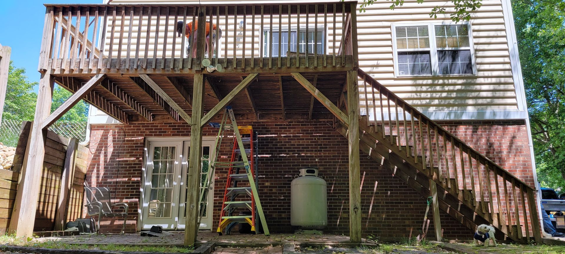 A wooden deck is being built on the side of a brick house.