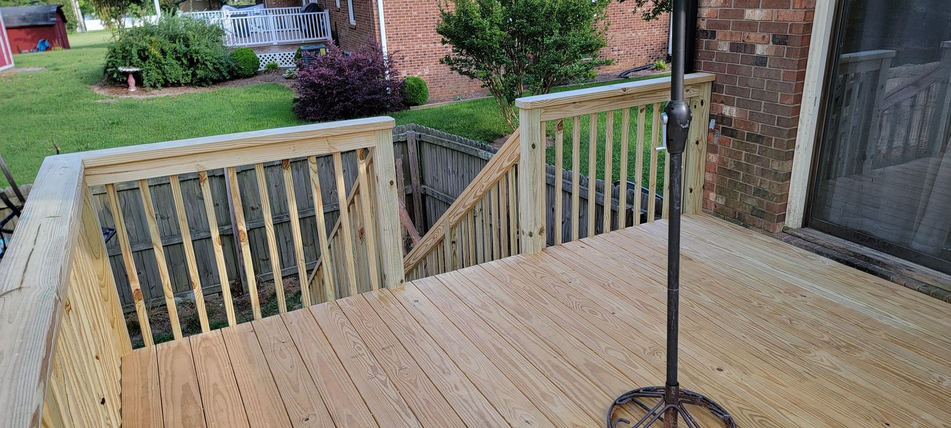 A wooden deck with stairs and an umbrella on it.