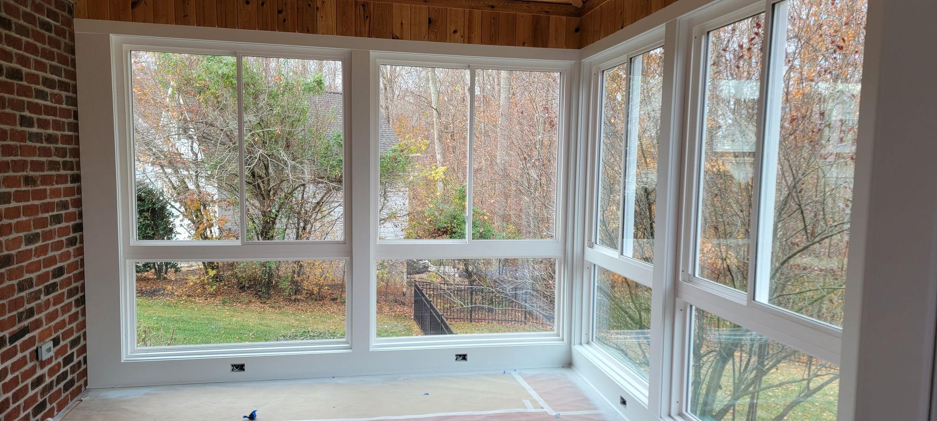 A screened in porch with lots of windows and a brick wall.