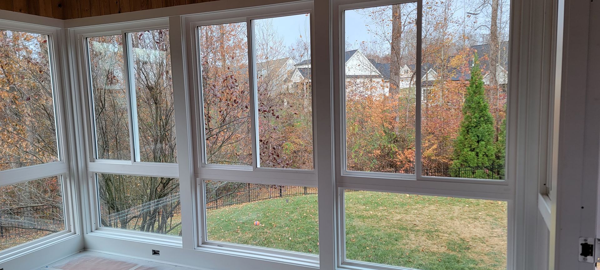 A screened in porch with lots of windows and a view of the backyard.