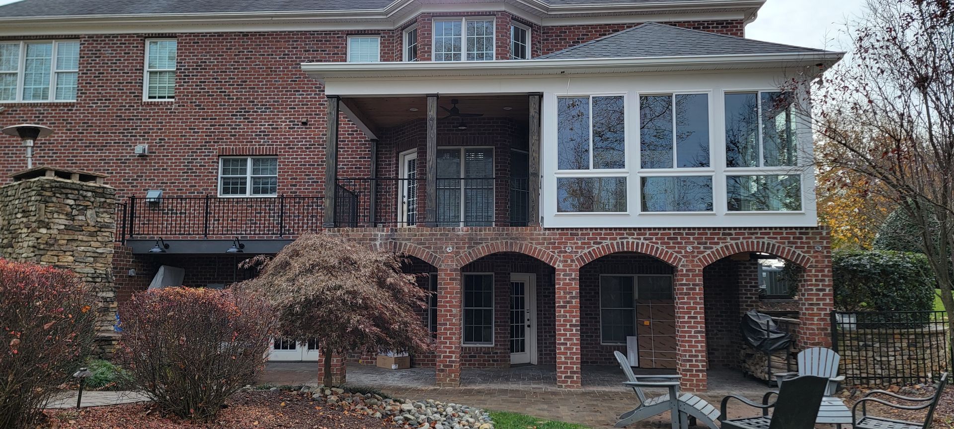 A large brick house with a screened in porch and patio.