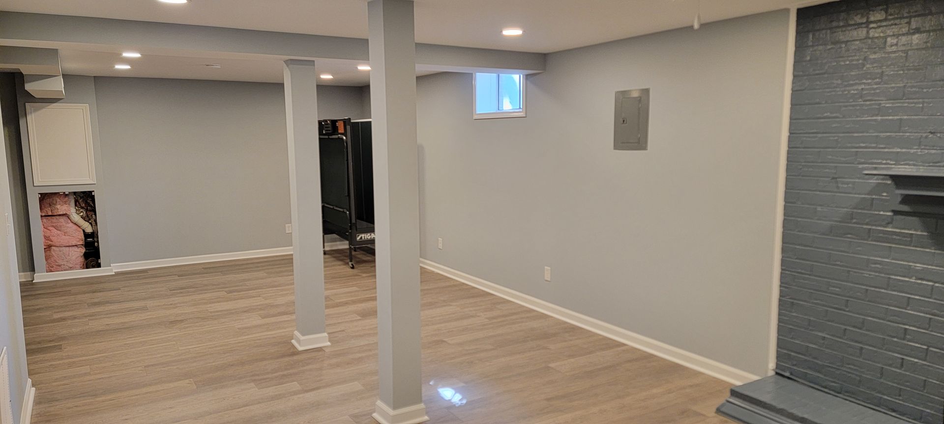 An empty basement with a fireplace and a window.