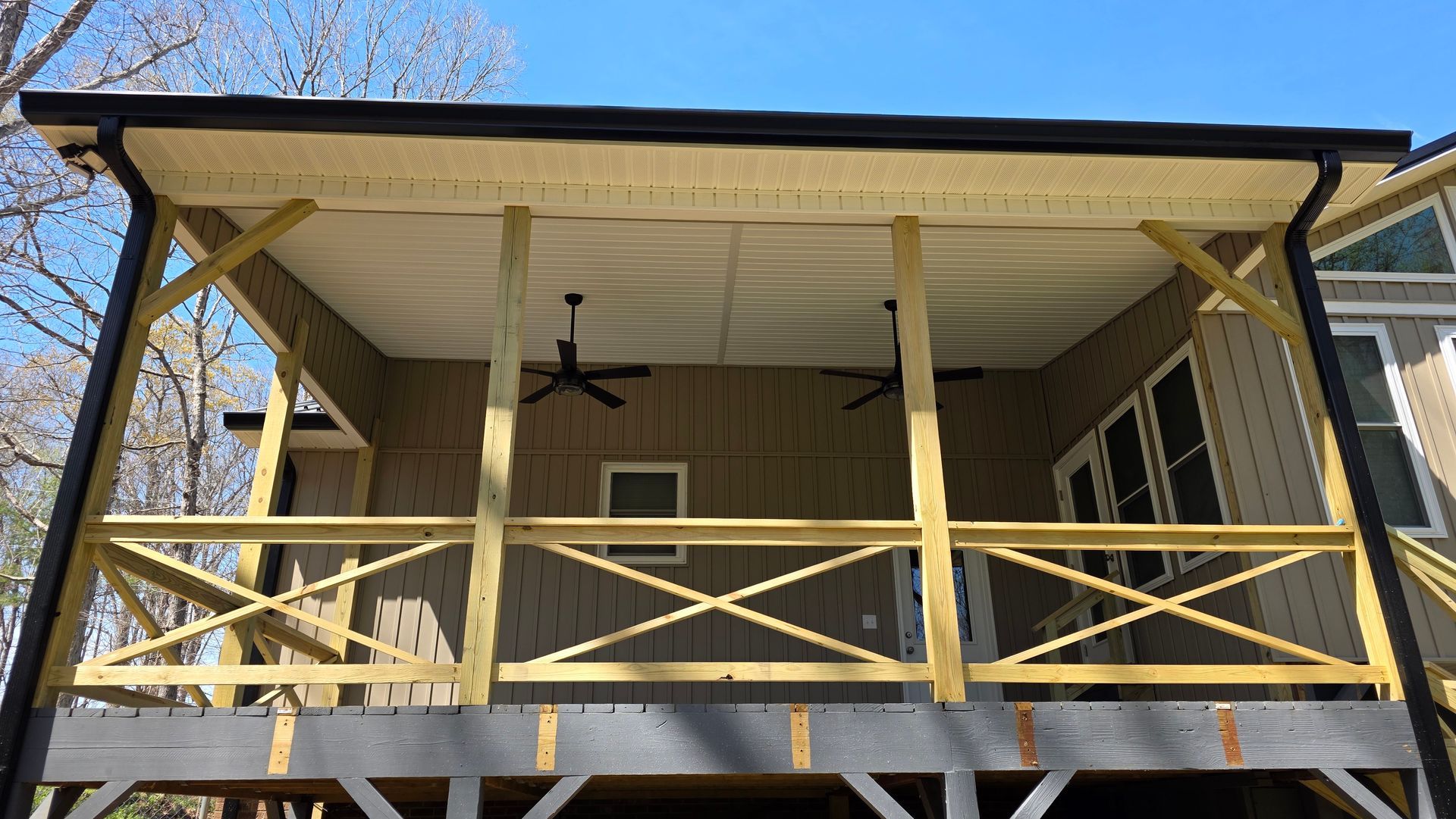 A wooden porch with a ceiling fan on a house.