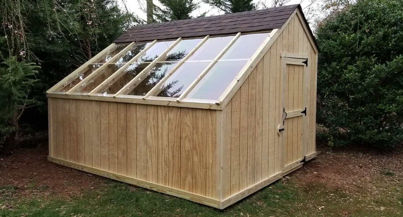 A wooden shed with a greenhouse attached to it.