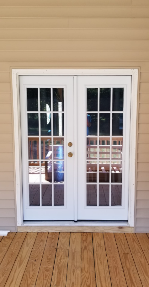 A pair of white french doors on a wooden deck.