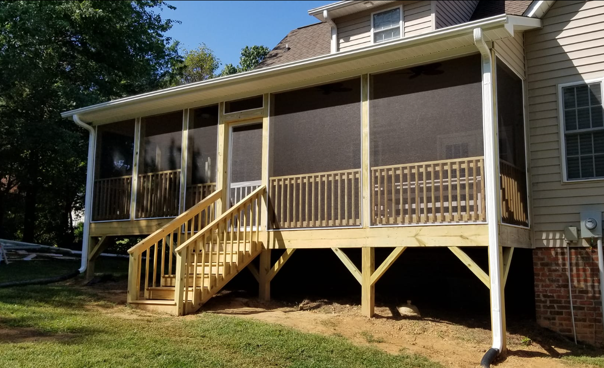 Wooden screened-in porch attached to a house, with stairs leading down to a grassy yard.