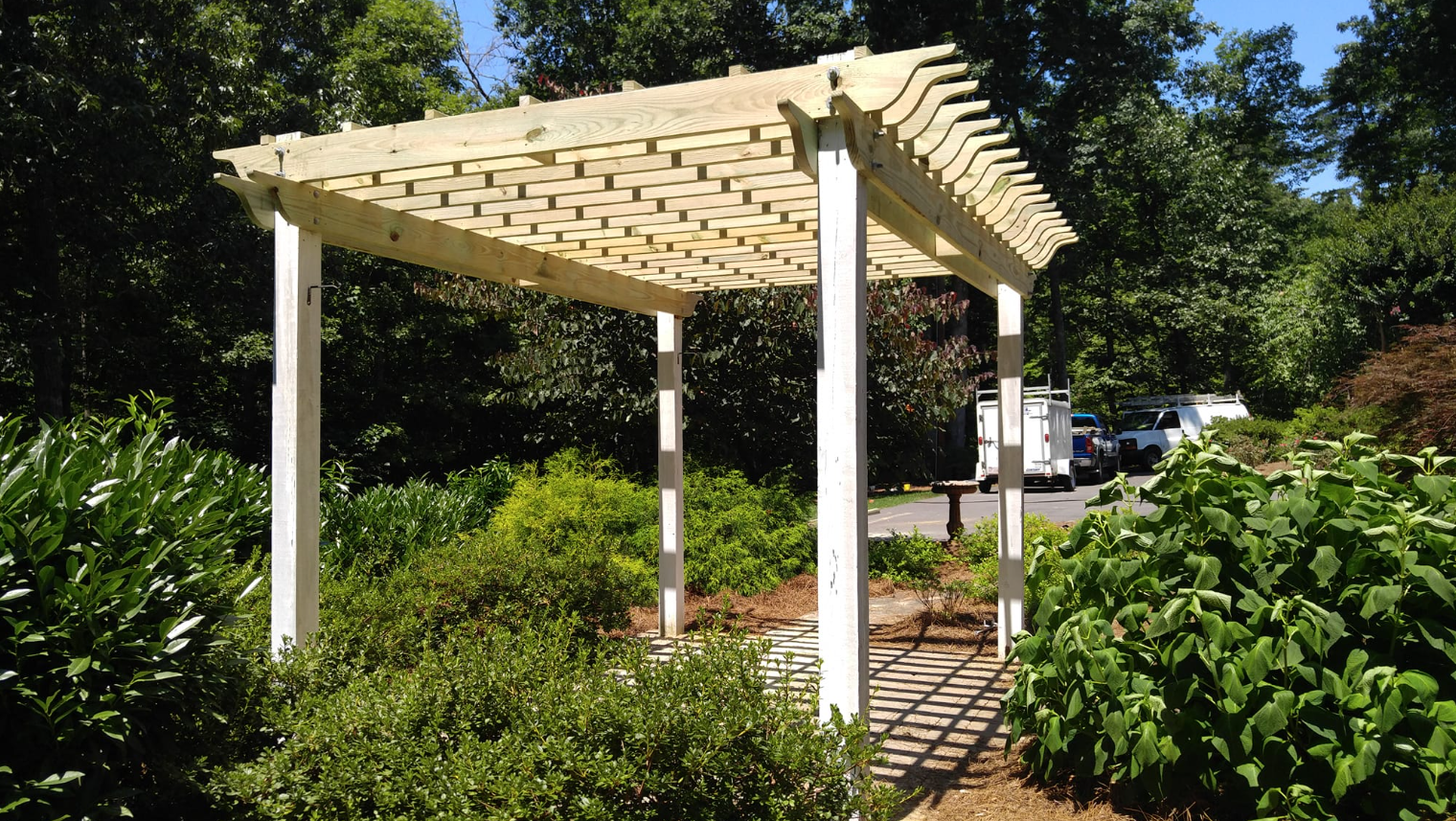 A white pergola is in the middle of a garden