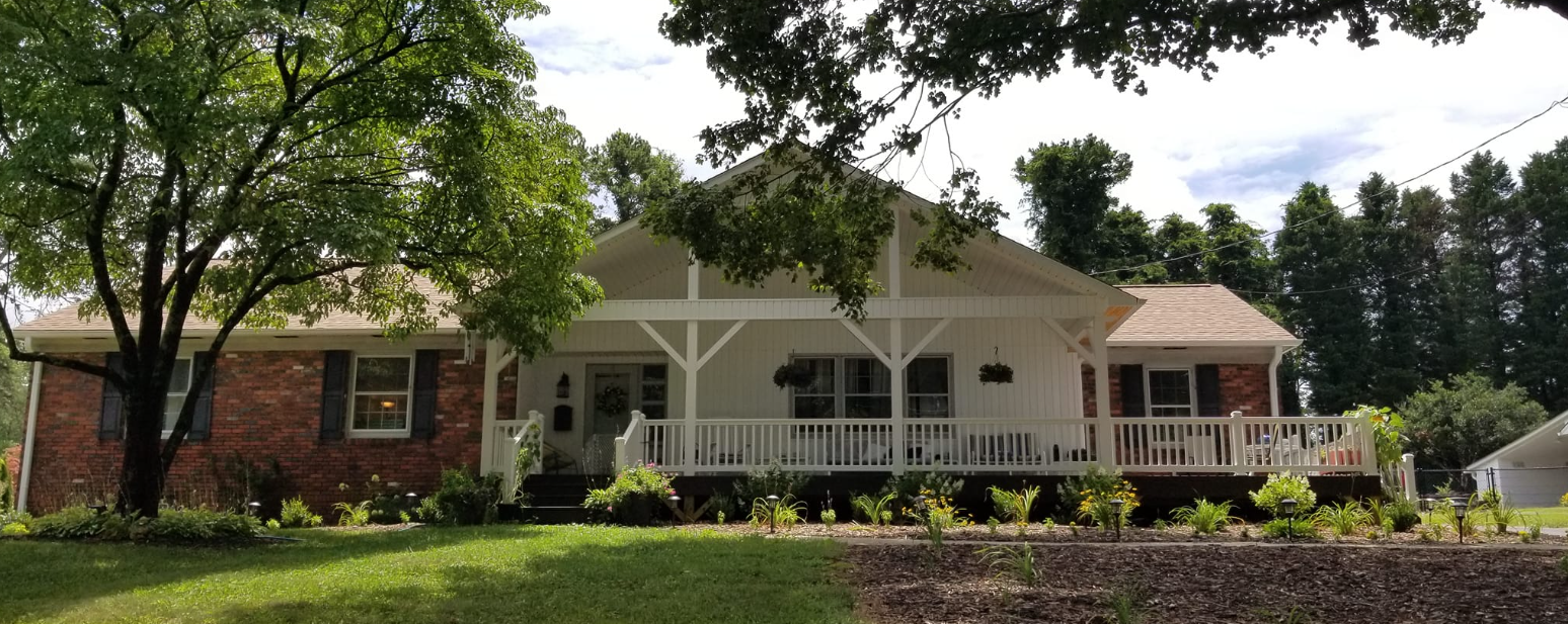 A large brick house with a porch and trees in front of it