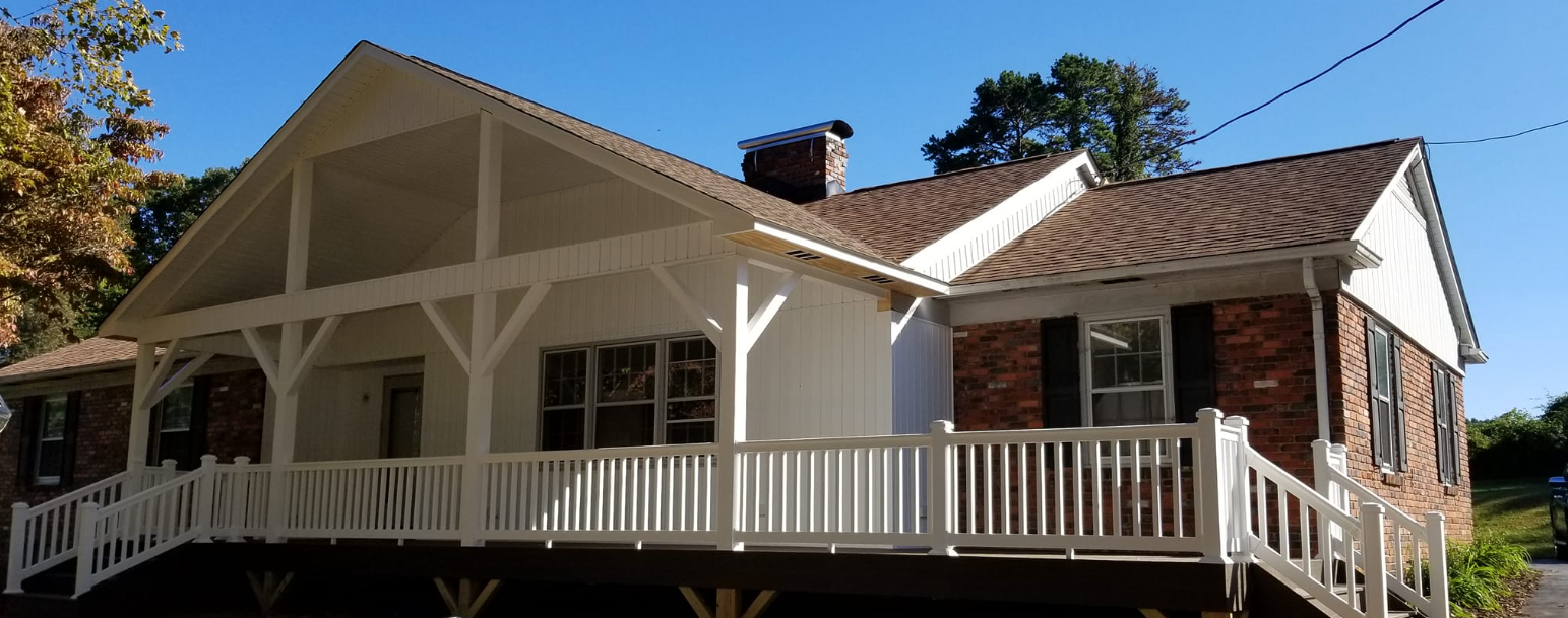 A large brick house with a large deck and a white railing.