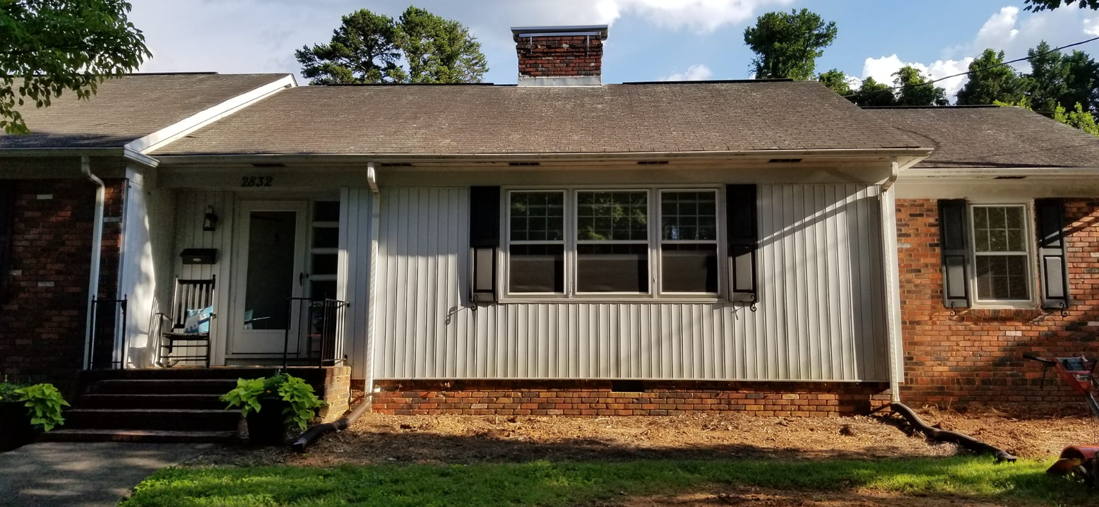 A brick house with a white siding and black shutters.
