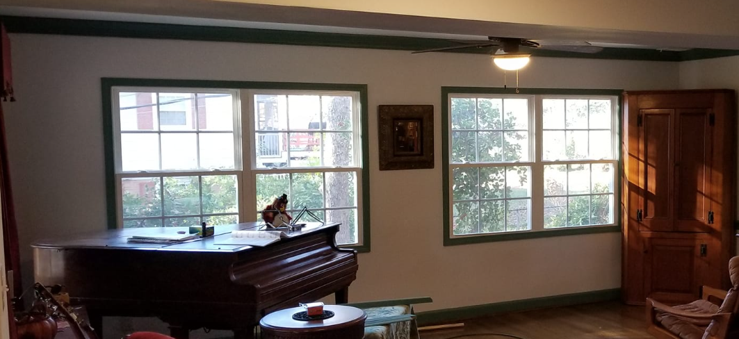 A living room with a piano and lots of windows