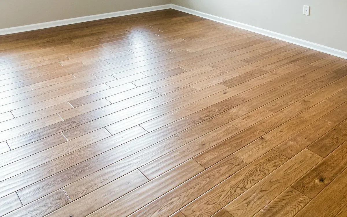 An empty room with hardwood floors and a white trim.