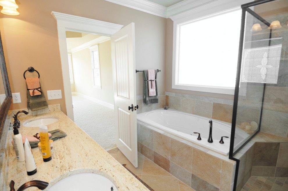 A bathroom with a tub , sink , mirror and shower.