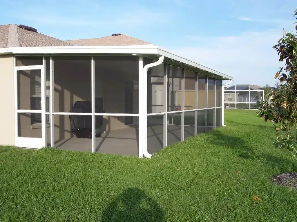 A screened in porch in the backyard of a house