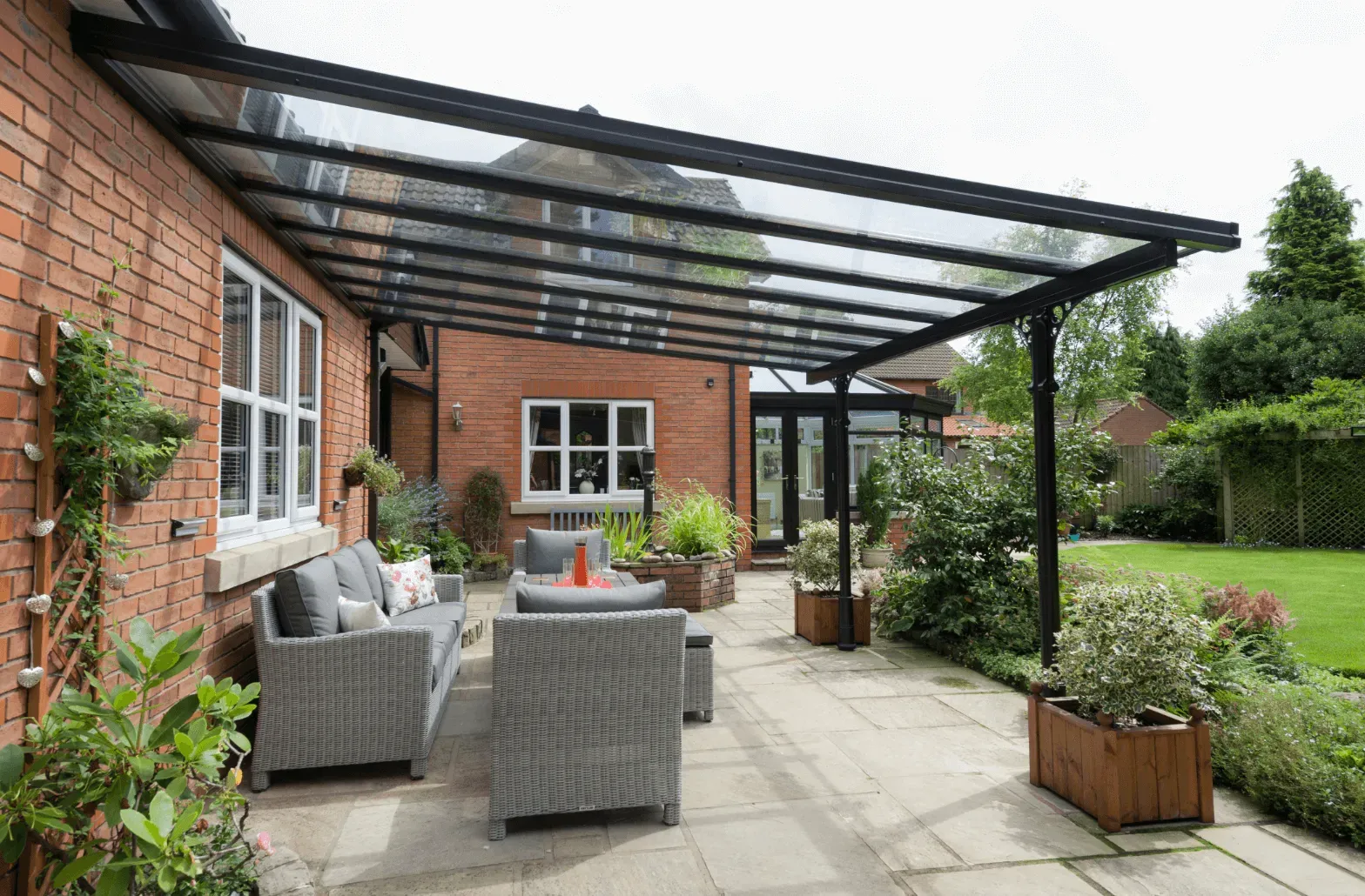 There is a patio with a canopy over it and a brick building in the background.