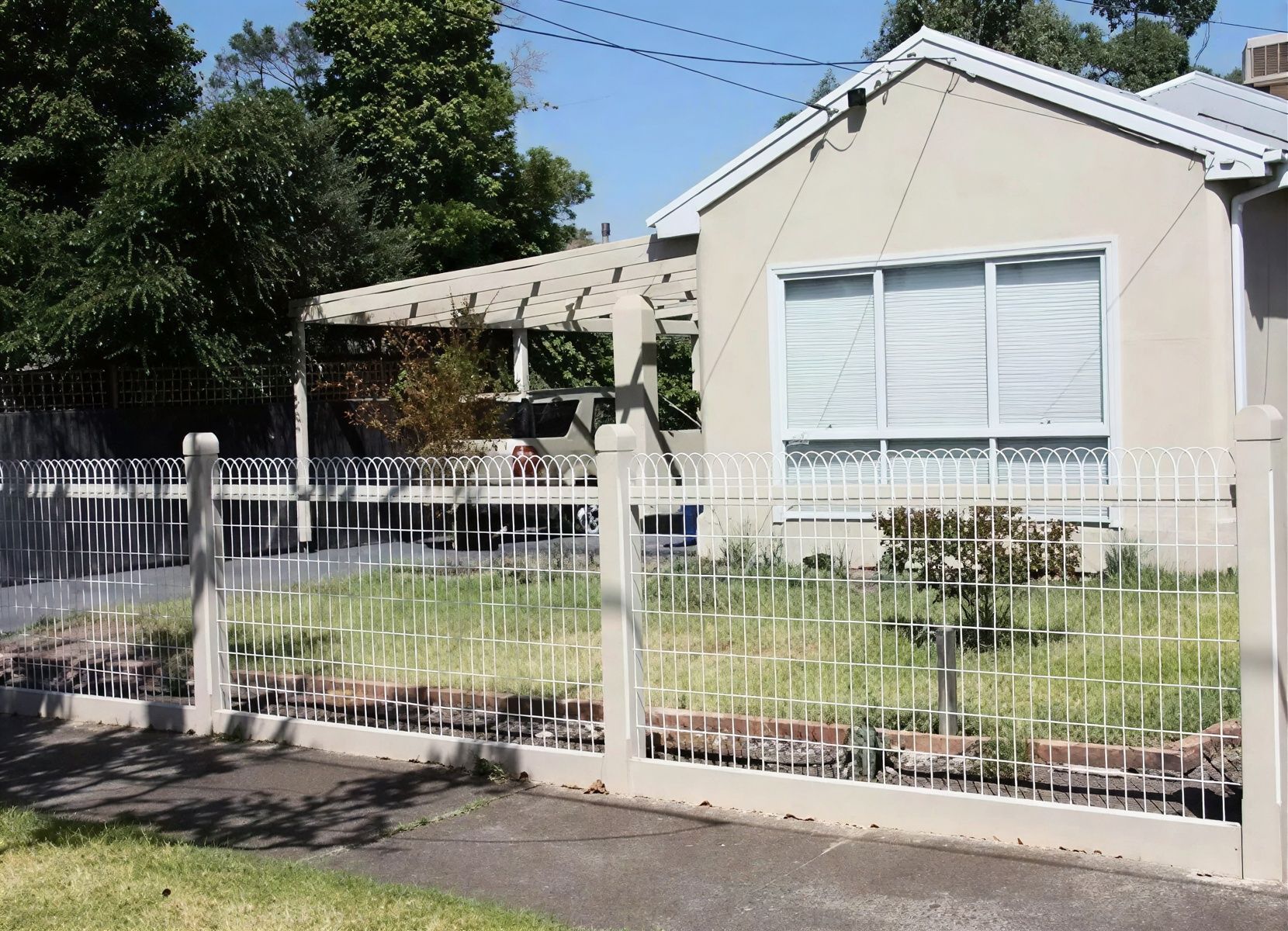 A quaint house with a small yard is enclosed by a wire fence