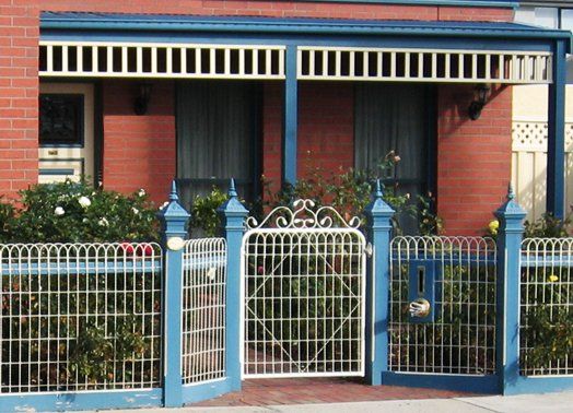 Brick house with blue trim, wrought iron gate, and small garden.