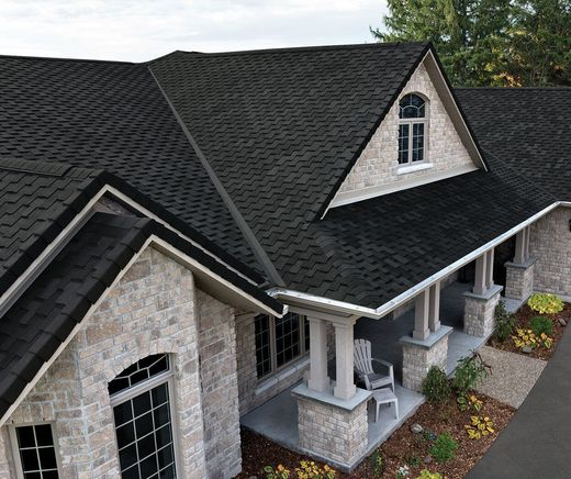Stone house exterior with dark shingled roof, white trim, and a front porch entrance