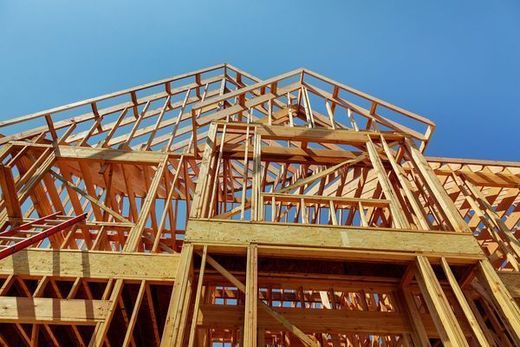 Wooden house frame under construction against a clear blue sky