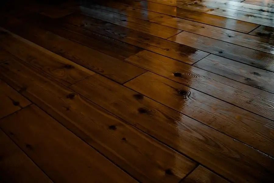 Dark wooden floorboards with light reflections and knots