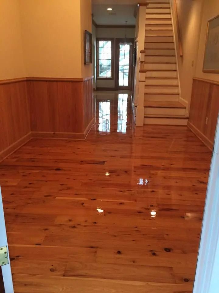 Shiny hardwood hallway with wood-paneled walls, stairs on the right, and glass doors at the far end.