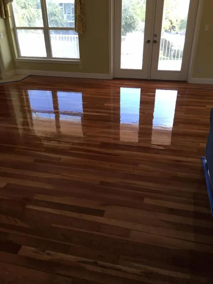 Empty room with glossy hardwood floor and sliding glass doors opening to a deck.