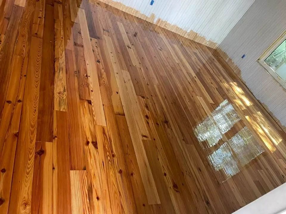 Shiny hardwood floor in an empty room with white walls and a window reflection