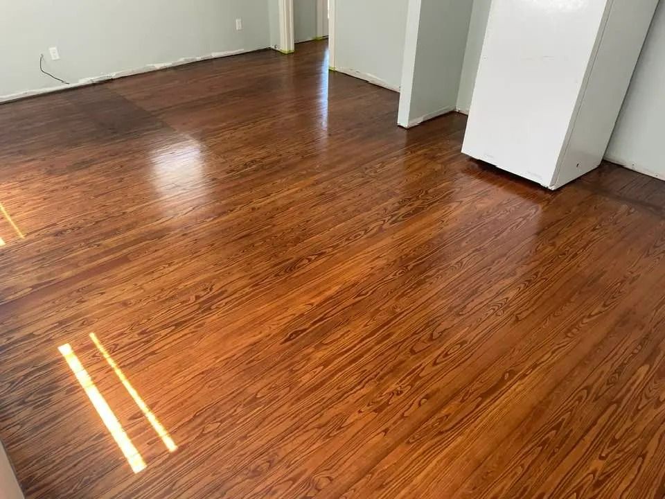 Empty room with polished hardwood floors and sunlight reflections near white walls and doorways