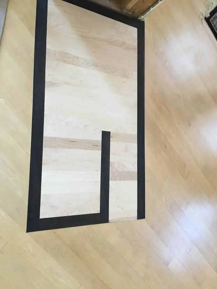 Black tape outlines a rectangular maze on a light wood floor.
