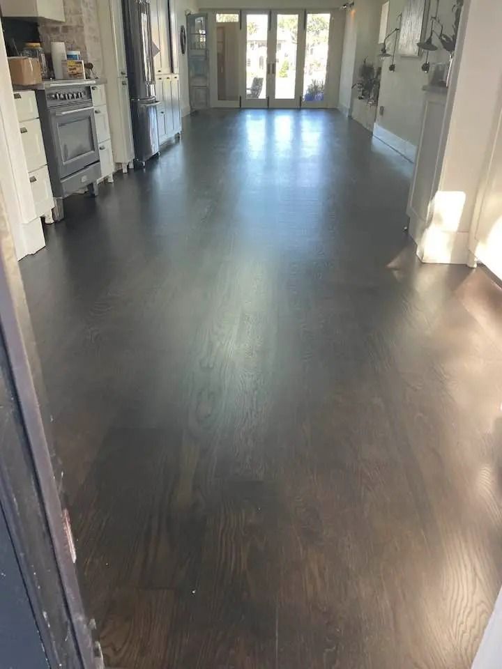 Empty hallway with dark wood floors and bright windows at the far end