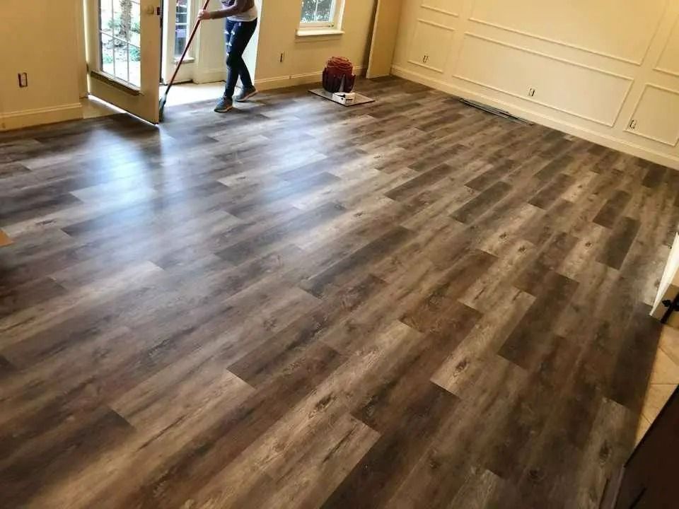 Empty room with gray wood flooring and open double doors, with a person near the back wall.