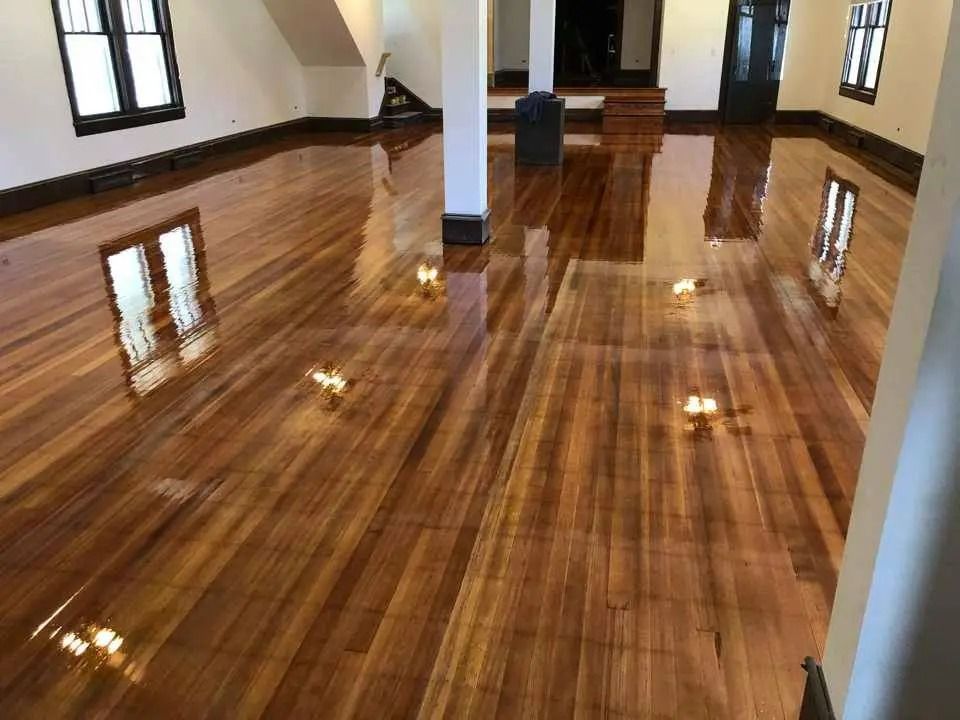 Glossy hardwood floor in a bright empty room with windows and white walls