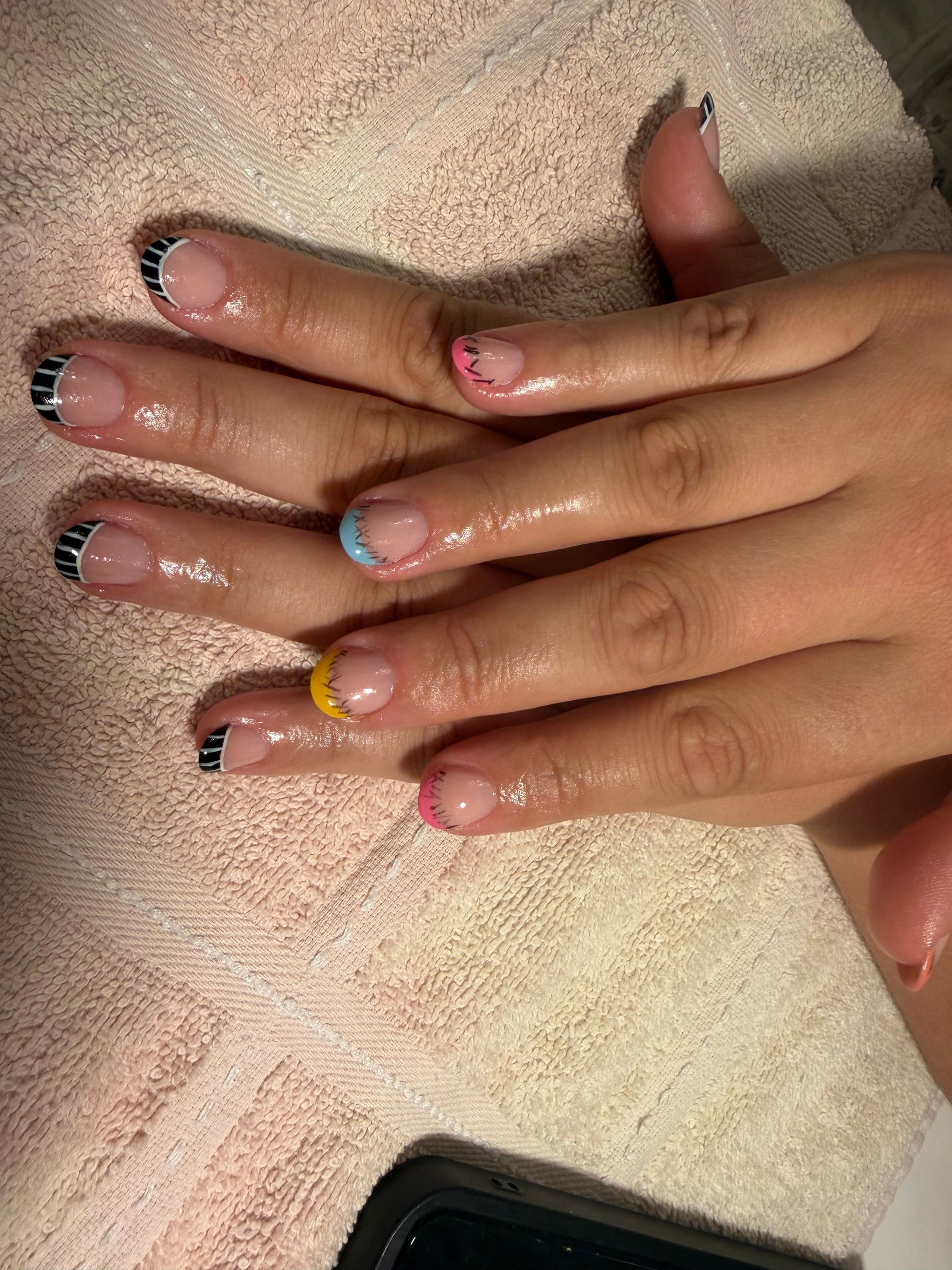 Vier Hände mit glänzendem Nageldesign und Strasssteinen auf einem beigen Handtuch.