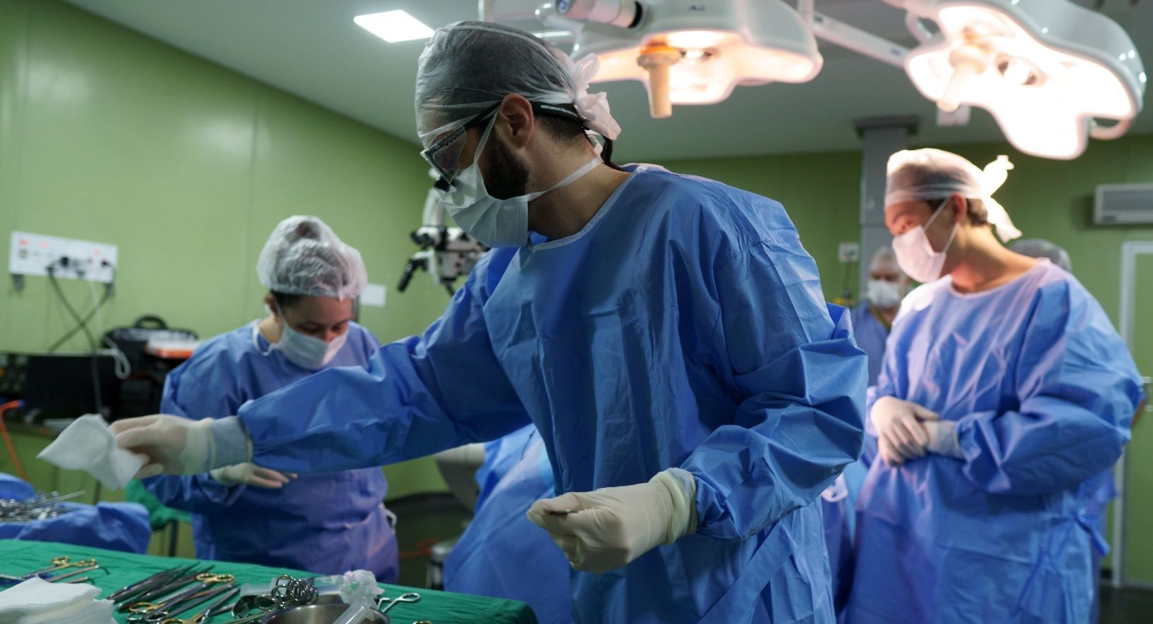 Equipe cirúrgica em centro cirúrgico durante procedimento de descompressão do nervo facial