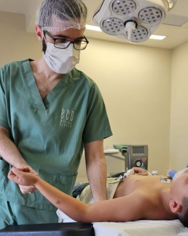 Dr. Thomas Marcolini em centro cirúrgico avaliando paciente, referência no tratamento da Meralgia Parestésica complexa.