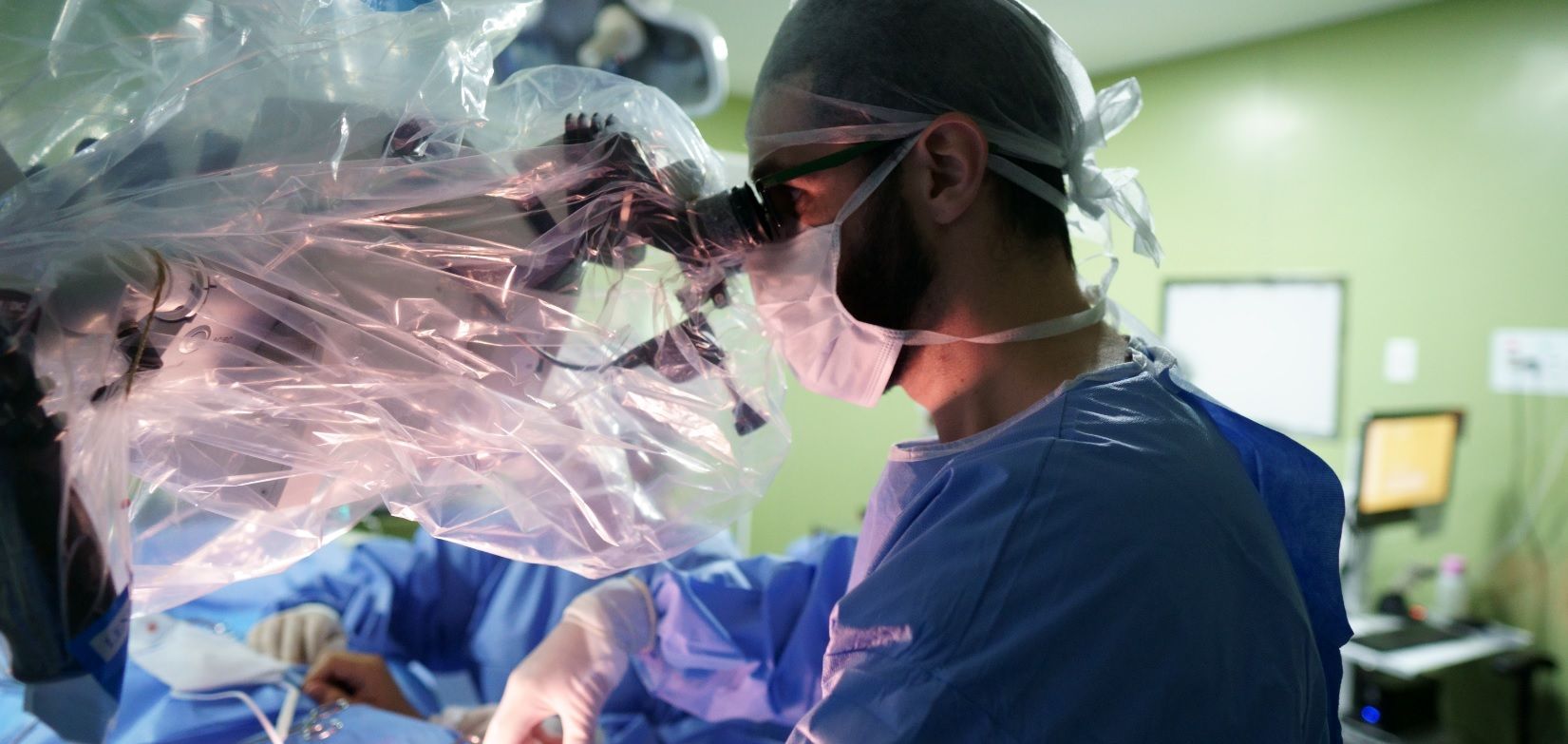 Dr. Thomas Marcolini operando ao microscópio cirúrgico, especialista em meralgia parestésica