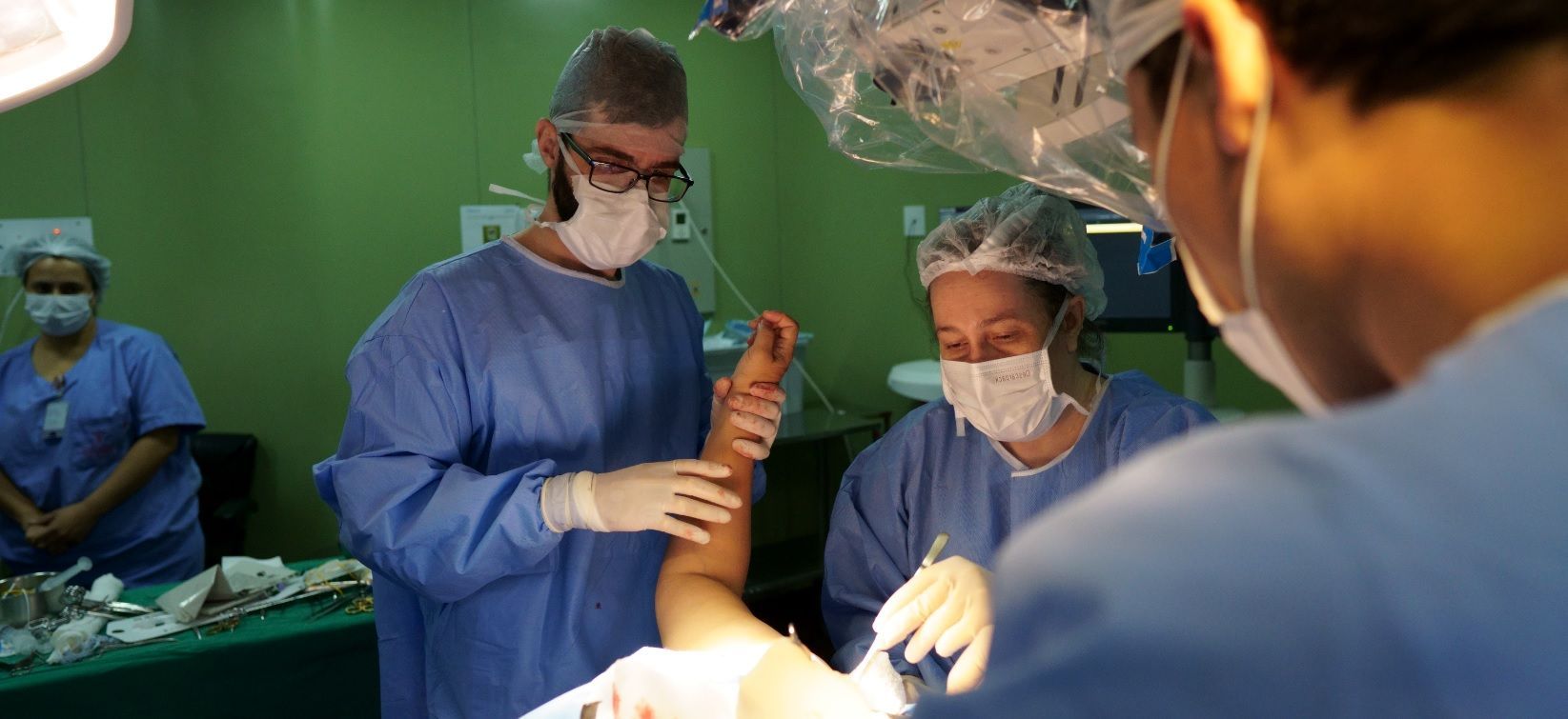 Equipe cirúrgica segurando braço de paciente durante cirurgia de sequelas do plexo braquial