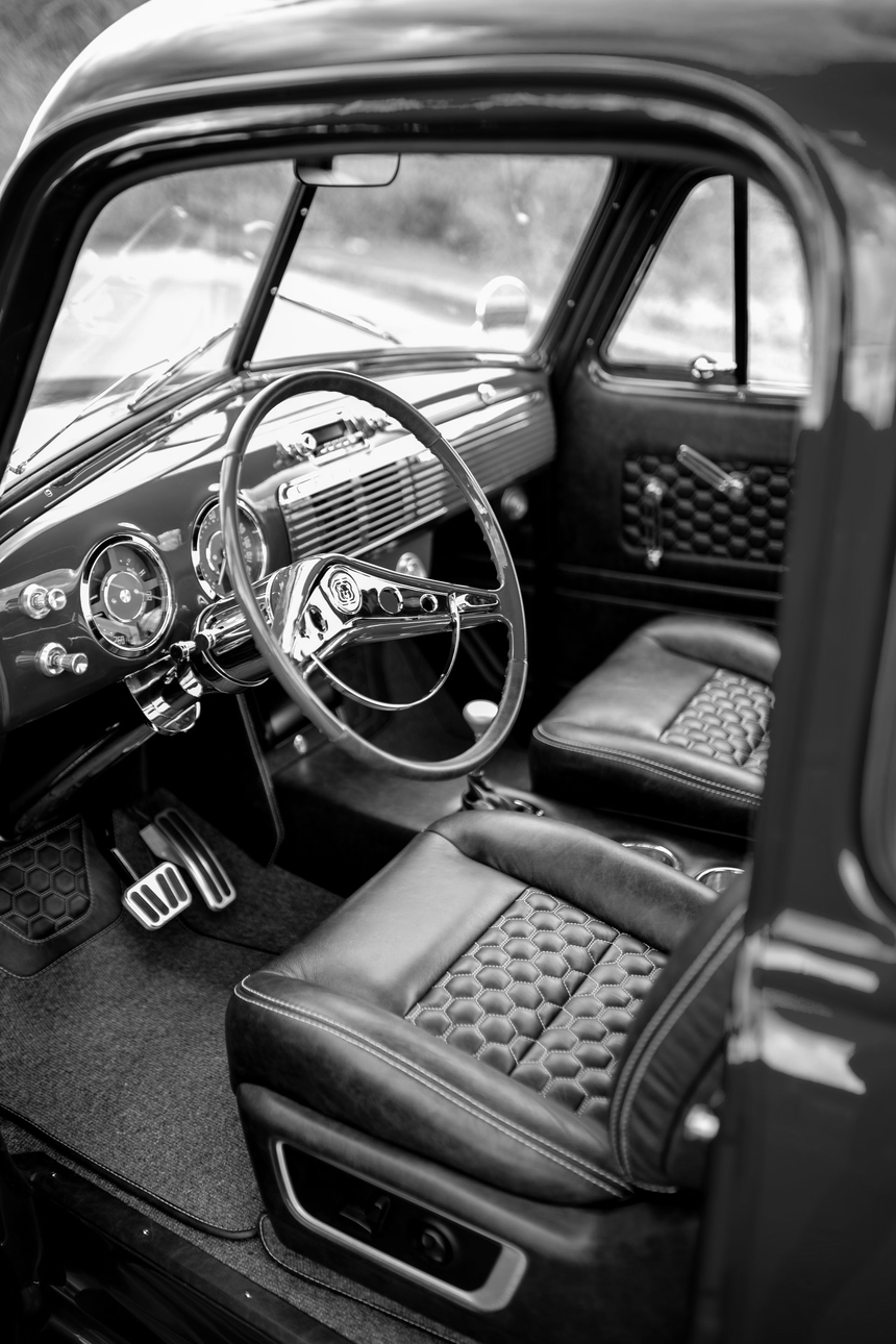Classic car interior with quilted leather seats, chrome steering wheel, and dashboard details