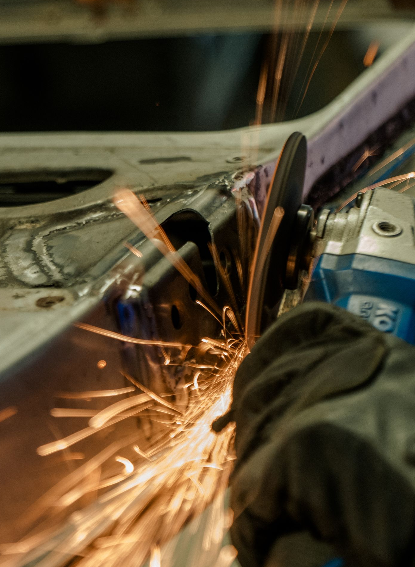 Worker using a grinder on metal, sending bright orange sparks across the surface