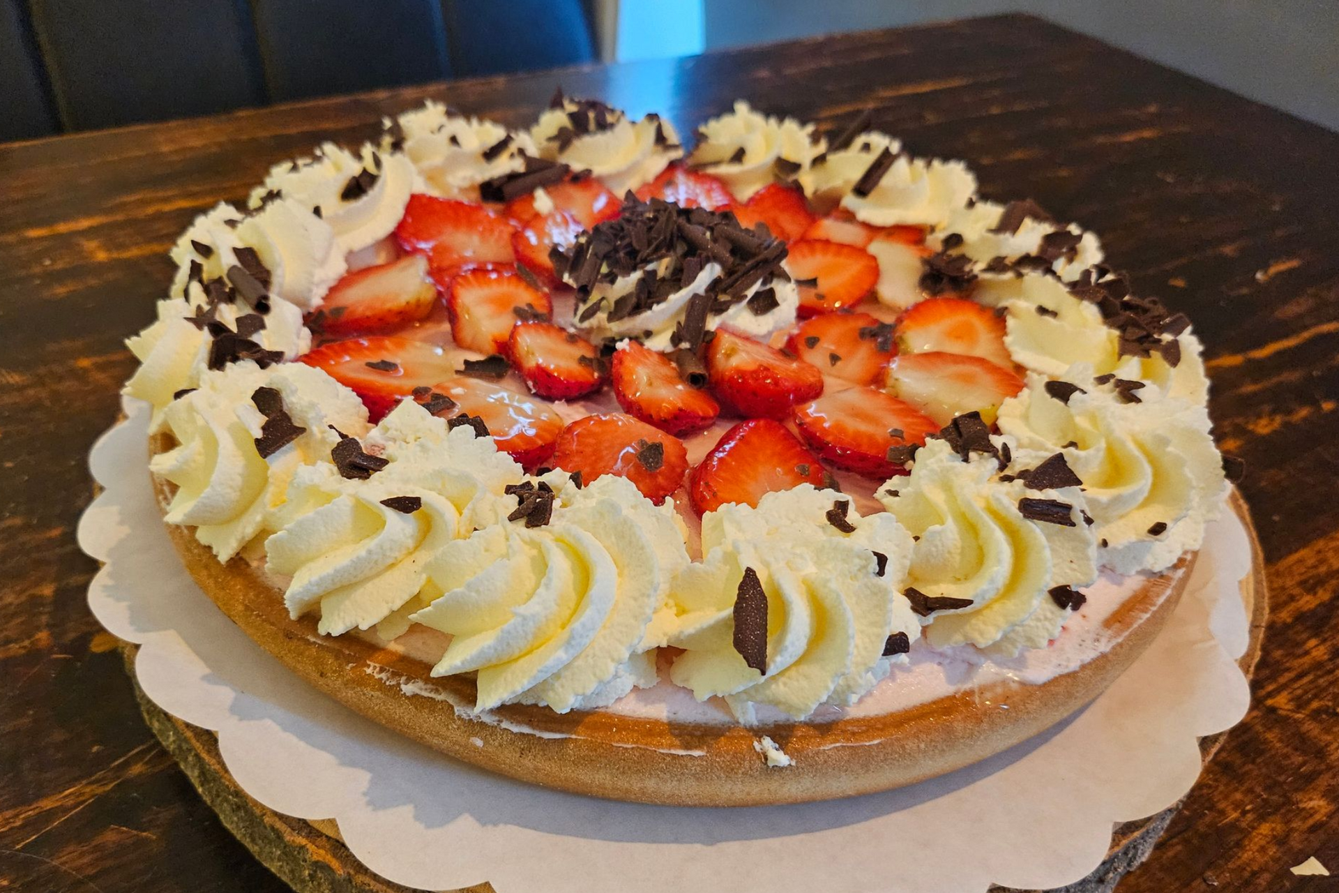 Een aardbeientaart met slagroomkrullen en stukjes pure chocolade erop.