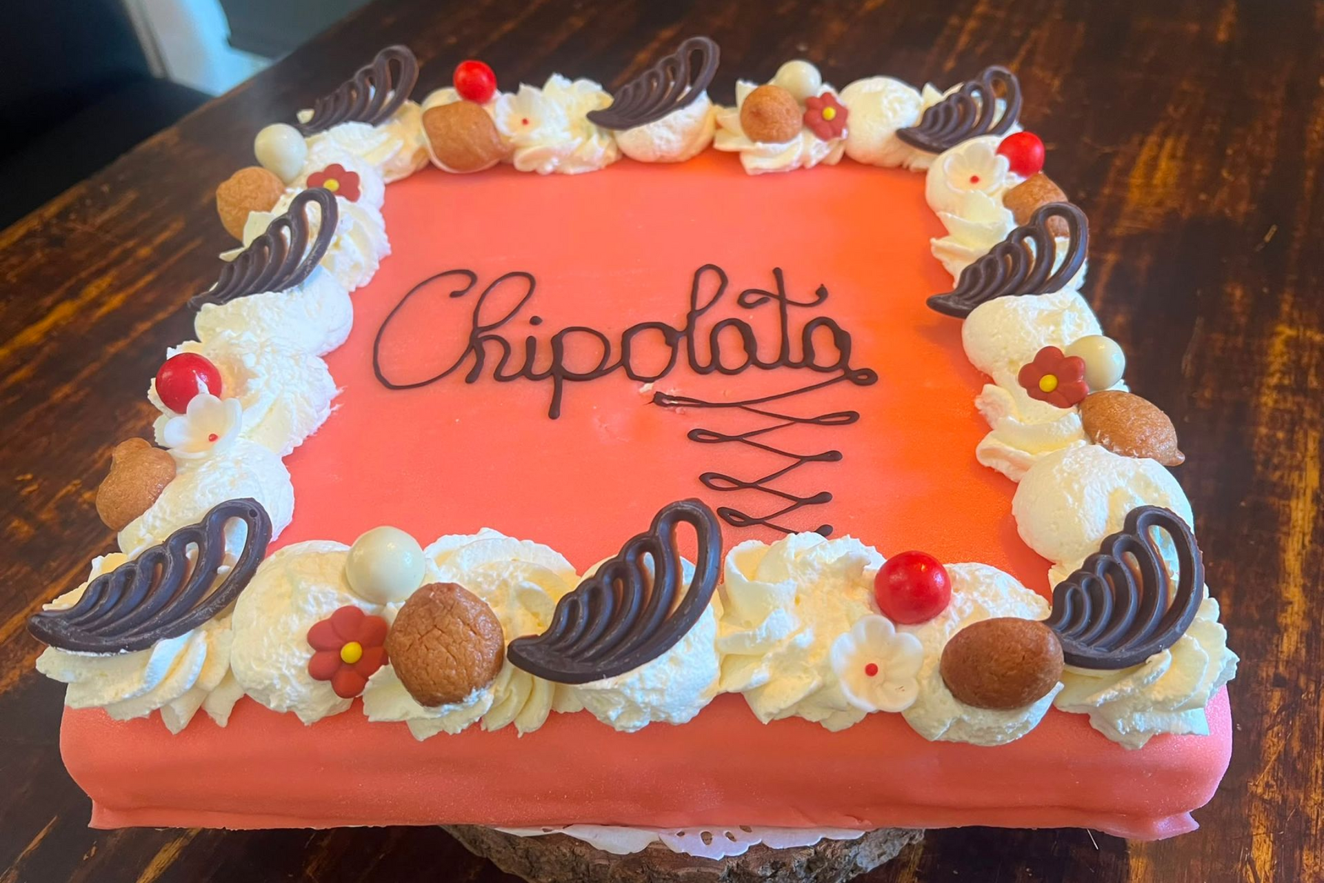 Chipolata taart met glazuur, slagroom en chocoladeversiering, en daar bovenop het woord 