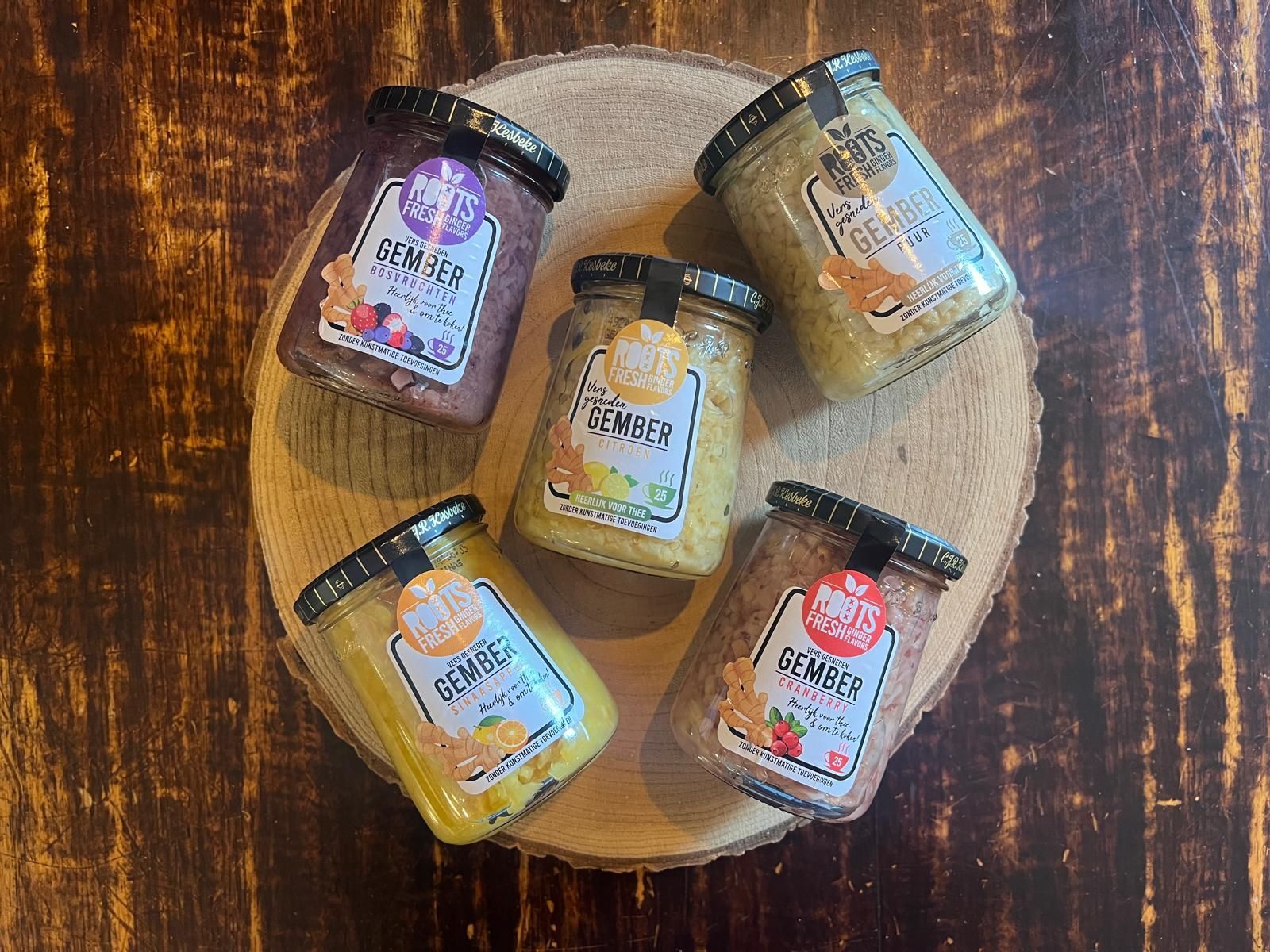 Vijf gemberpotten op een ronde houten plank op een donkere houten tafel.