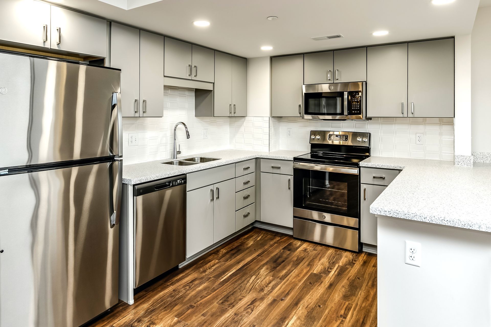 Modern kitchen with stainless steel appliances, white cabinets, and wood floors