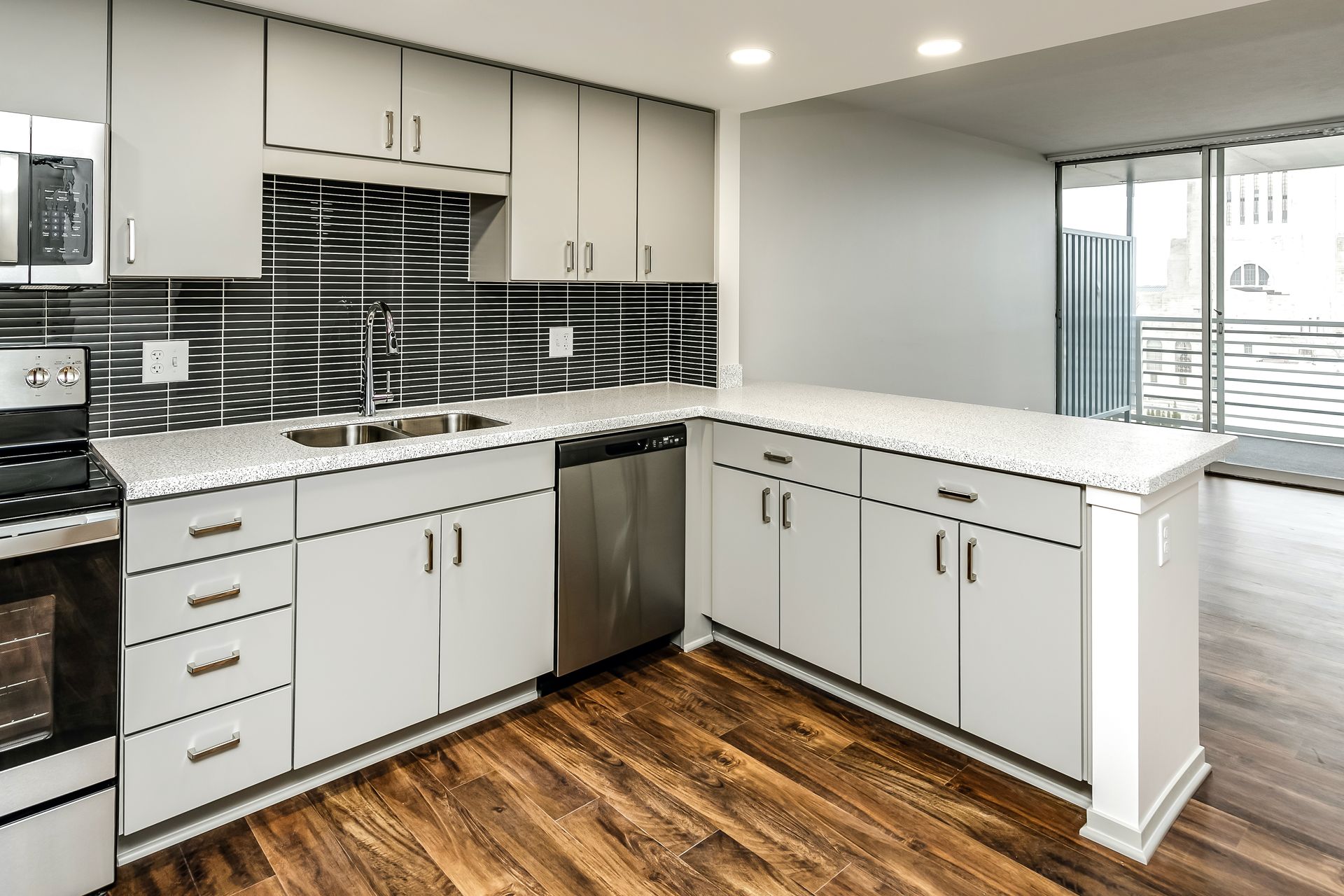 Modern white kitchen with gray backsplash, stainless appliances, and wood flooring