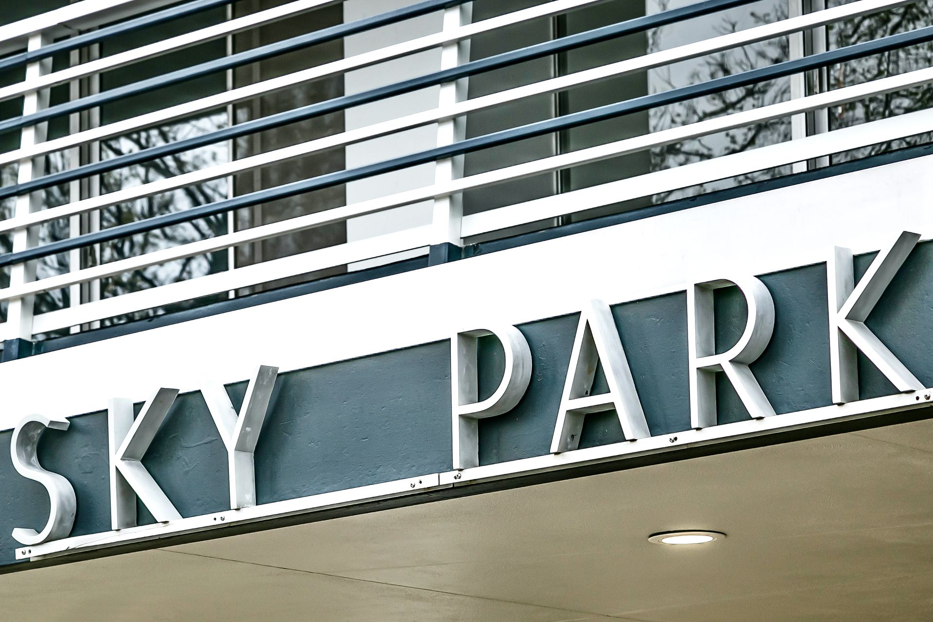 “SKY PARK” sign on a building facade with white railings above